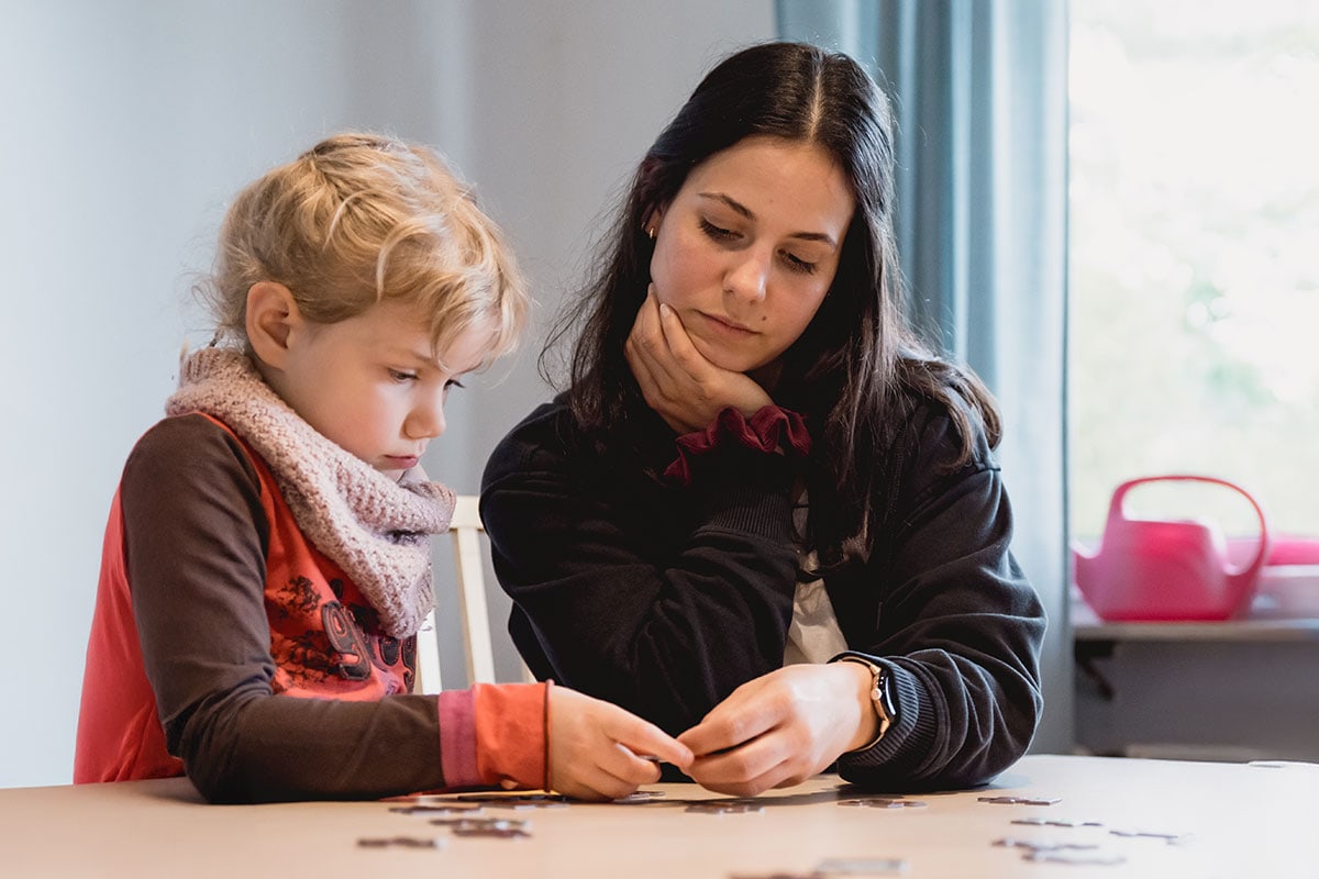 Ein Erwachsener und ein Kind lösen gemeinsam ein Puzzle